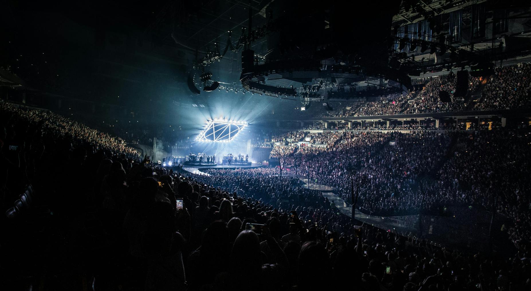 A packed concert arena with bright stage lights